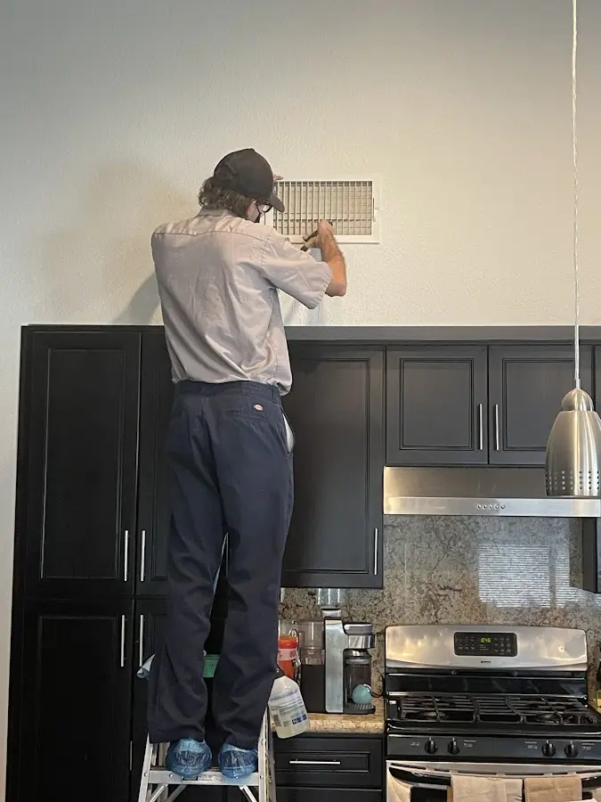 Technician inspecting an air vent during HVAC service in Baldwin